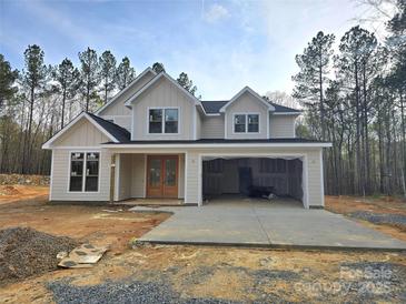 Charming two-story home with light beige siding, black roof, and an open two-car garage nestled in a wooded lot at 44401 Us 52 N Hwy, Richfield, NC 28137