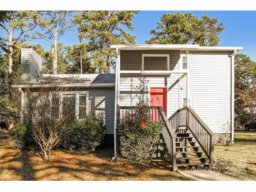 Charming home featuring light siding, a chimney, front stairs and a red front door, surrounded by mature trees at 1052 Palmyra Dr, Fort Mill, SC 29708