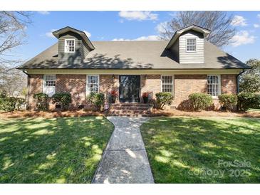 Charming brick home with dormer windows, manicured landscaping, and a welcoming walkway to the front door at 1148 Turnbridge Rd, Charlotte, NC 28226