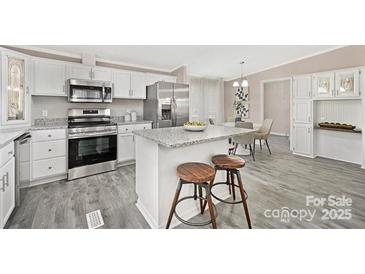 Modern kitchen features stainless steel appliances, granite countertops, and a center island with bar stool seating at 140 Sanford Ln, Badin Lake, NC 28127