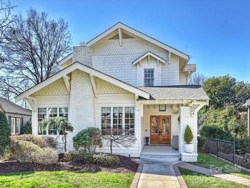 Charming white two-story home with a brick chimney, manicured landscaping and a walkway to the front door at 2004 Lombardy Cir, Charlotte, NC 28203