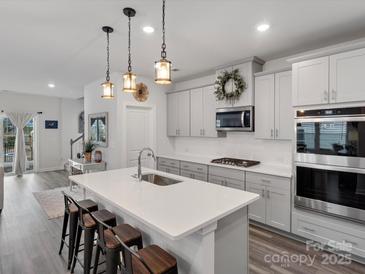 Open-concept kitchen featuring a center island, pendant lighting, and modern appliances at 518 Palmarosa St, Fort Mill, SC 29715