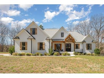 A charming white brick house with a manicured lawn, dark window frames, and wooden shutters under a blue sky at 9260 Ahavah Ln, Indian Trail, NC 28079