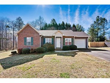 Charming brick home featuring green shutters, a well-manicured lawn, and attached garage at 2107 Summerfield Cir, Conover, NC 28613