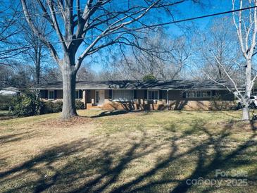 Charming single-story brick home featuring a well-manicured lawn and mature trees at 1006 Coulwood Dr, Charlotte, NC 28214