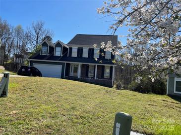 Charming two-story home featuring dark shutters and a well-maintained lawn on a sunny day at 12662 Woodside Falls Rd, Pineville, NC 28134