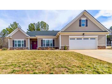 Charming single-story home featuring a two-car garage, well-manicured lawn, and inviting entrance with a decorative wreath at 136 Falls Leaf Dr, Troutman, NC 28166
