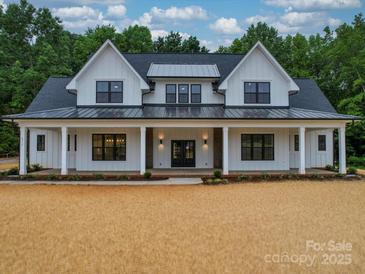 Stunning exterior of a two-story modern farmhouse with black trim windows and a welcoming front porch at 4024 Landsford Rd, Marshville, NC 28103