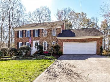 Traditional brick home with an attached two-car garage, green lawn and an American flag at 4522 Pendock Ct, Charlotte, NC 28226