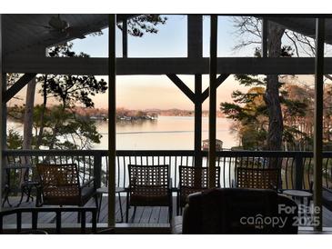 Inviting screened porch with water views, seating, and a glimpse of the serene lake at 547 Lake Shore Dr, Norwood, NC 28128