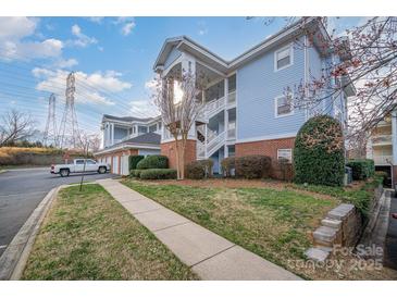 Inviting condo with blue siding, brick accents, and white stairs, set amidst green lawns and mature trees at 8629 Coralbell Ln, Charlotte, NC 28213