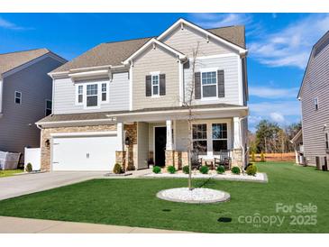 Charming two-story home featuring stone accents, a covered porch, manicured lawn and a two car garage at 187 Tetcott St, Mooresville, NC 28115