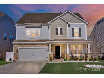 Elegant two-story home with stone accents, a two-car garage, and a charming porch highlighted by evening light at 187 Tetcott St, Mooresville, NC 28115