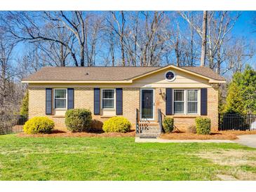 Charming one-story brick home featuring a well-manicured lawn and complementing shrubs at 1438 Plumstead Rd, Charlotte, NC 28216