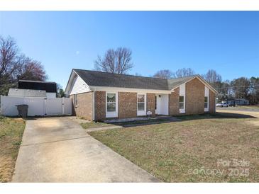 Charming brick home featuring a well-manicured lawn, a long driveway, and a classic design under a clear blue sky at 9100 Clancy Pl, Charlotte, NC 28227