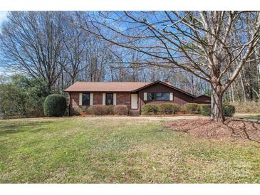 Charming brick home featuring a well-manicured lawn and mature trees, creating an inviting curb appeal at 10007 Mountain Apple Dr, Mint Hill, NC 28227
