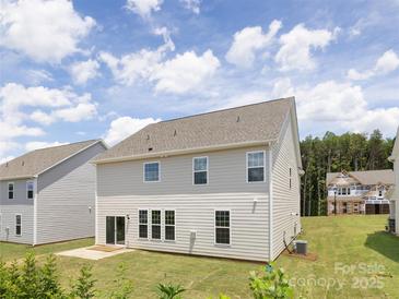 View of the home's rear exterior, showcasing the siding, windows, and a spacious backyard at 122 Asmodean Ln, Troutman, NC 28166