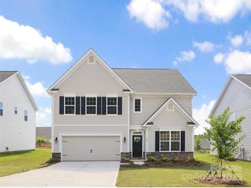 Charming two-story home features a modern design, manicured lawn, attached garage, and welcoming entrance at 122 Asmodean Ln, Troutman, NC 28166