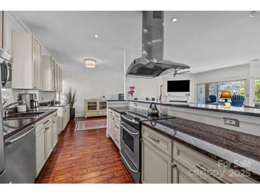 Bright kitchen features stainless steel range hood, granite countertops, wooden floors and views into the living room at 224 N Poplar St # 9, Charlotte, NC 28202
