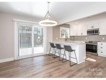 Modern kitchen with white cabinetry, stainless steel appliances, subway tile backsplash and breakfast bar with seating at 2628 Park Rd # F, Charlotte, NC 28209
