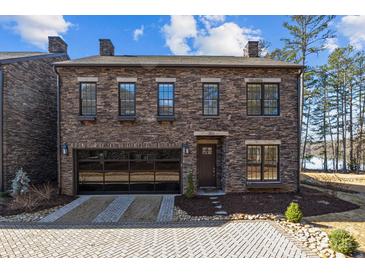 Charming two-story stone home featuring a glass garage door and manicured landscaping at 302 Ambleside Village Ln, Davidson, NC 28036