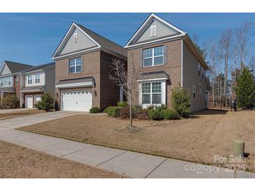 Two-story brick home showcasing a well-maintained lawn and attached two-car garage, offering curb appeal at 4856 Pepper Dr, Harrisburg, NC 28075