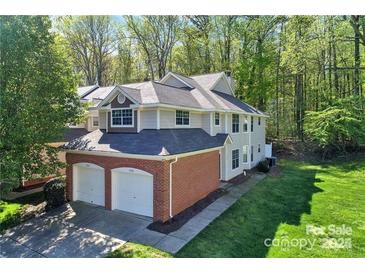 Two-story home features attached two-car garage, and a landscaped yard on a wooded lot at 5921 Amity Springs Dr, Charlotte, NC 28212