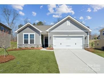 Charming home featuring a two-car garage, stone accents, manicured lawn, and beautiful curb appeal at 9932 Manor Vista Trl, Kannapolis, NC 28027