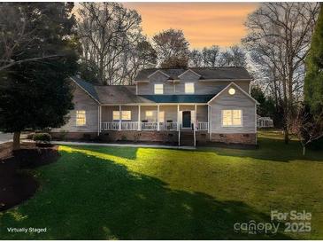 Charming two-story home featuring a welcoming front porch and lush, green lawn at dusk at 107 Doris Ct, Lincolnton, NC 28092