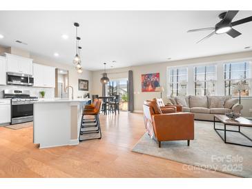 Inviting living space featuring a modern kitchen, a cozy sitting area, and stylish hardwood floors at 2024 Linn Cv, Waxhaw, NC 28173