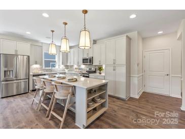 Bright kitchen with white cabinetry, stainless steel appliances and a large center island with seating at 407 Sunharvest Ln, Indian Trail, NC 28079