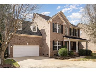 Traditional brick home with attached garage, manicured lawn, and classic architectural details at 5672 Wrenfield Ct, Charlotte, NC 28277