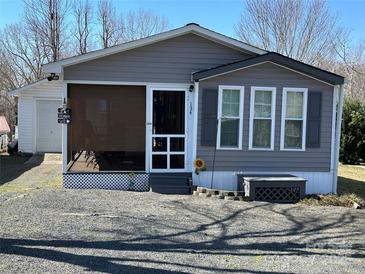 Charming home featuring gray siding, a screened porch, and a small garden area at 134 Cardinal Ave, New London, NC 28127