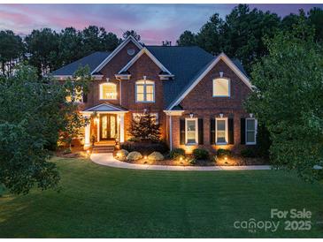 Stunning two-story brick home with manicured lawn, landscape lighting, and mature trees at 14314 Lissadell Cir, Charlotte, NC 28277
