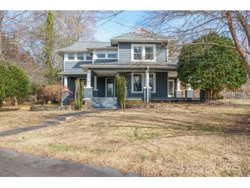Charming blue two-story home featuring a cozy front porch and mature trees at 1740 12Th Street Nw Dr, Hickory, NC 28601