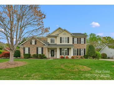 Charming home showcasing a manicured lawn, brick and vinyl exterior, complemented by blooming flowers at 2711 Liberty Hall Ct, Waxhaw, NC 28173