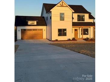 Charming two-story farmhouse-style home with a large driveway and a welcoming front porch at 1300 Austin Chaney Rd, Wingate, NC 28174