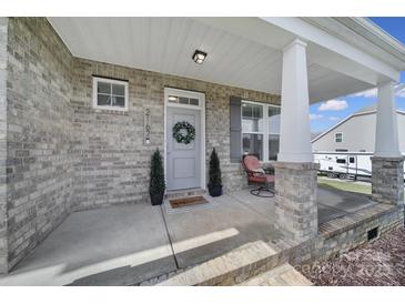 Inviting front porch featuring brick columns, a cozy sitting area, and a decorative wreath on the front door at 2167 Whispering Winds Dr, Rock Hill, SC 29732