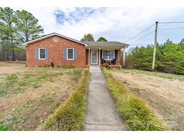 Charming brick home with a walkway leading to a covered front porch and beautifully landscaped yard at 36533 S South Stanly School Rd, Norwood, NC 28128