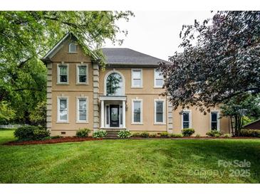 Stately two-story home with tan stucco, manicured lawn, and mature trees at 4825 1St Street Nw Ct, Hickory, NC 28601