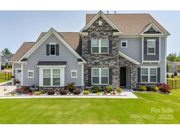 Charming two-story home featuring stone accents, a manicured lawn, and beautiful landscaping at 7133 Sumters Camp Trl, Fort Mill, SC 29707