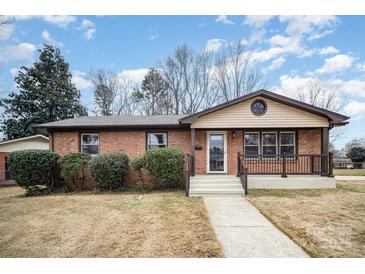 Charming brick home featuring a cozy front porch, manicured shrubs, and a well-maintained lawn at 5310 Myrica Ln, Charlotte, NC 28213