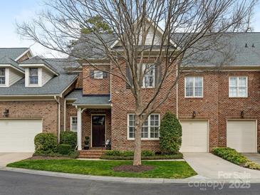 Charming brick townhome with a well-manicured lawn, two-car garage, and mature tree in front at 261 Crownsgate Ct, Charlotte, NC 28207