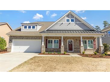 Charming brick home featuring a covered front porch, two-car garage and beautiful architectural details at 2934 Hiddenbrook Way, Fort Mill, SC 29707