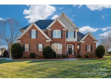 Stately brick home featuring a manicured lawn, dormers, and black shutters at 8018 Cotton St, Harrisburg, NC 28075