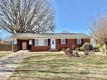 Charming red brick home with a well-manicured lawn and a covered carport, perfect for suburban living at 911 Union Ter, Gastonia, NC 28056