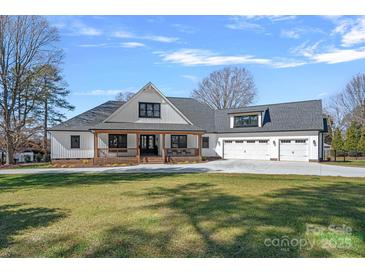 Stunning white modern farmhouse featuring a three car garage and a welcoming front porch at 106 Beachview Dr, Mooresville, NC 28117