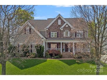 Charming two-story home with stone and siding exterior, a covered front porch, and a well-maintained lawn at 10823 Caverly Ct, Huntersville, NC 28078