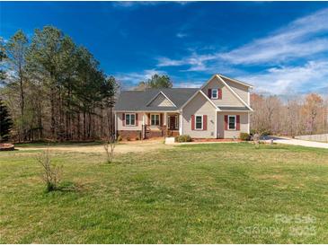 Charming two-story home featuring a landscaped yard, complemented by red shutters against the tan siding at 2050 Sunswept Ln, York, SC 29745