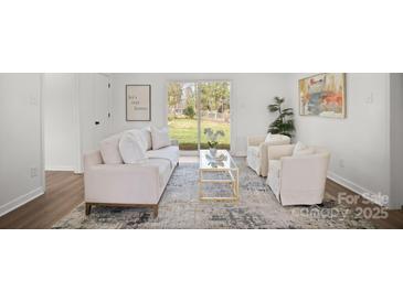 Cozy living room with white furniture, a glass coffee table, and sliding glass doors to the backyard at 2509 Lanecrest Dr, Charlotte, NC 28215